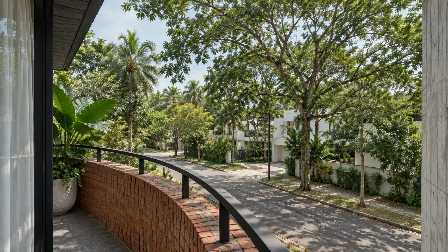 Balkon dengan pagar bata melengkung menghadap jalan dan pepohonan
